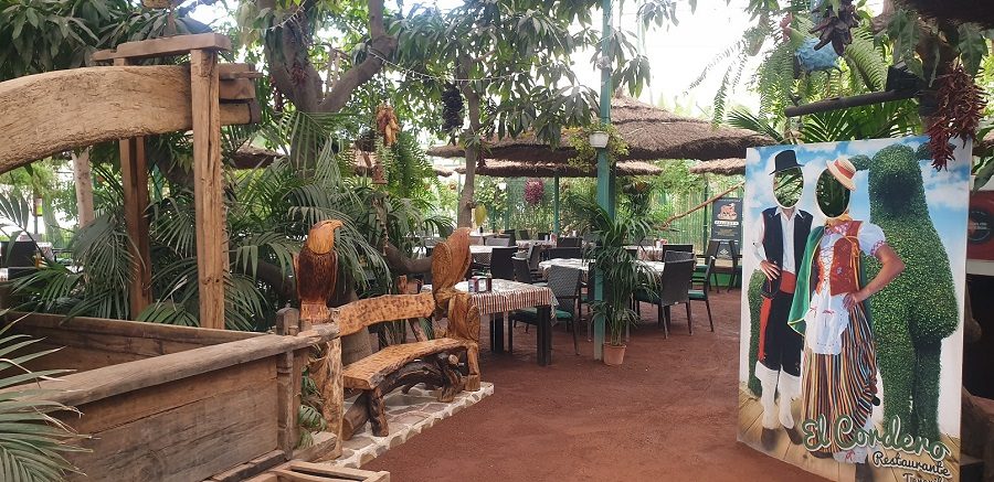 Interior del área Tropical de Restaurante El Cordero, con mesas, luces colgantes y vegetación